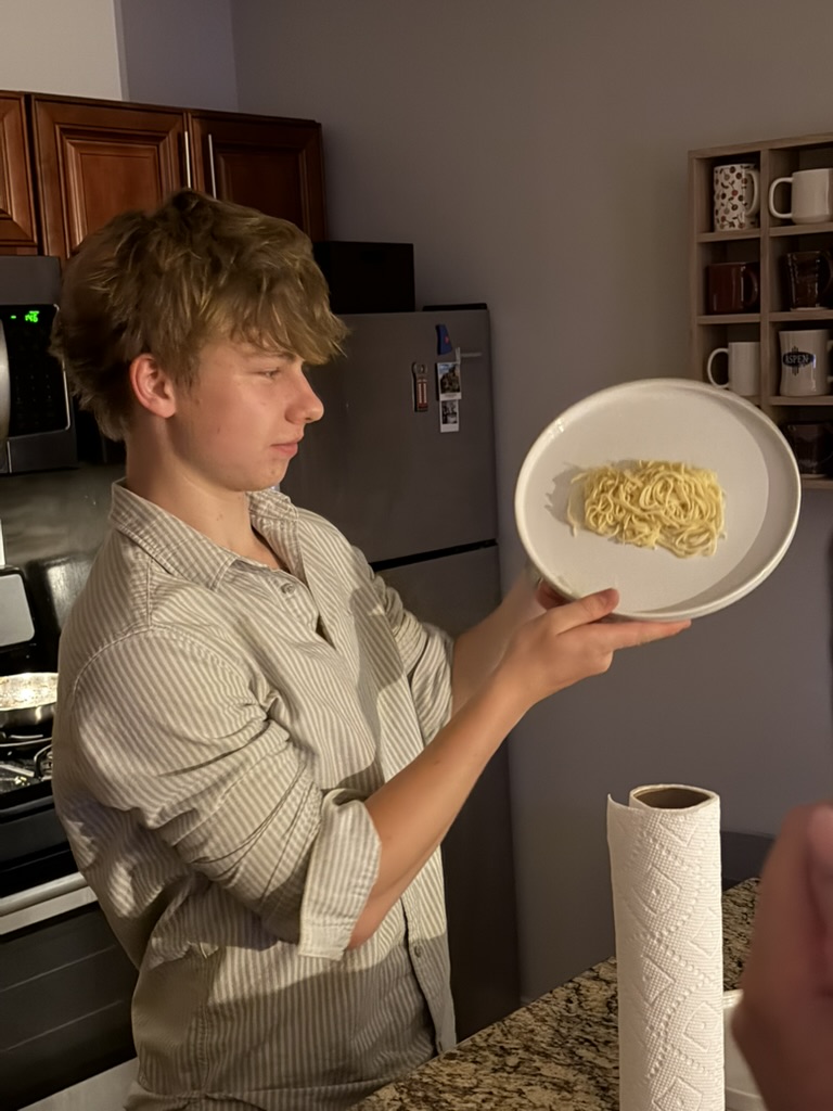 Robbie presenting a plate of pasta at a club practice dinner